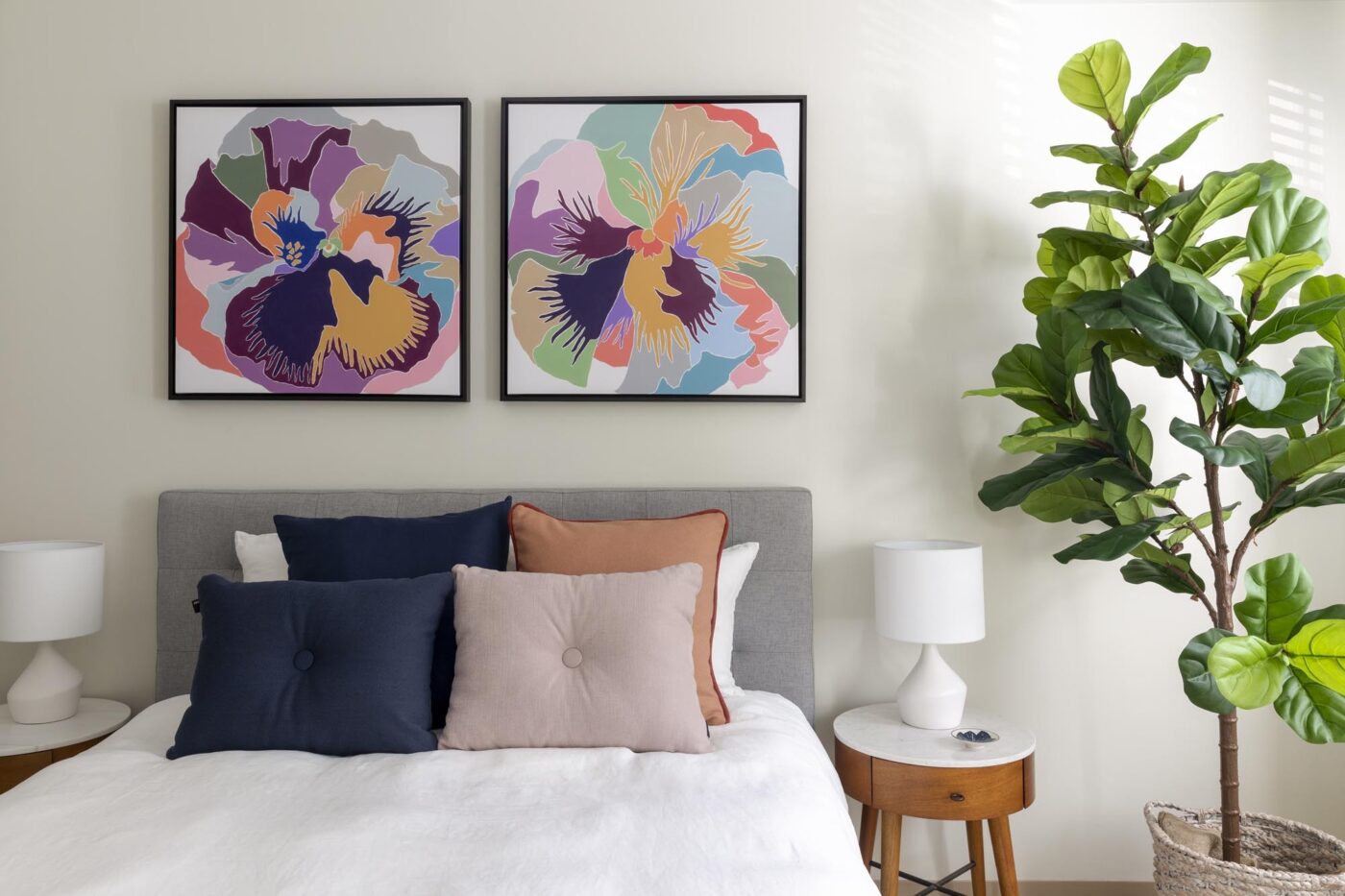 bed with large house plant and two floral paintings